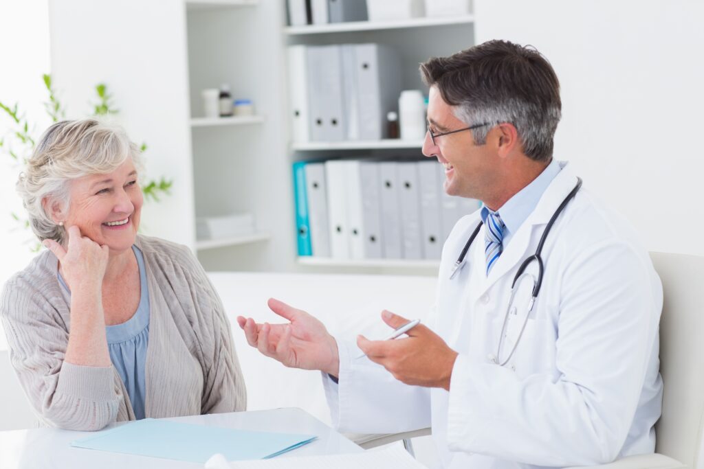 Doctor talking to elderly female patient in office, smiling