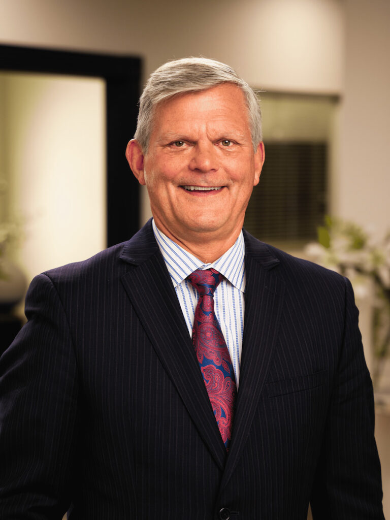 Net Revenue Employee, Bob, posing for headshot wearing a striped button up, tie, and black blazer, smiling