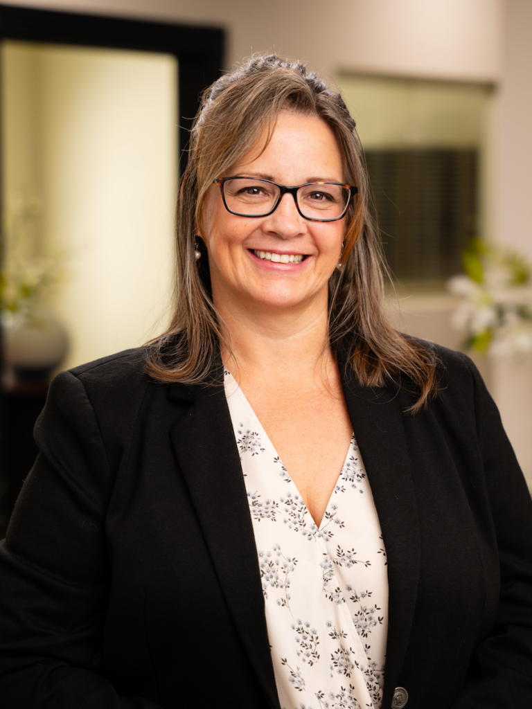 Net Revenue Employee, Carol, posing for headshot wearing blazer, white blouse and smiling