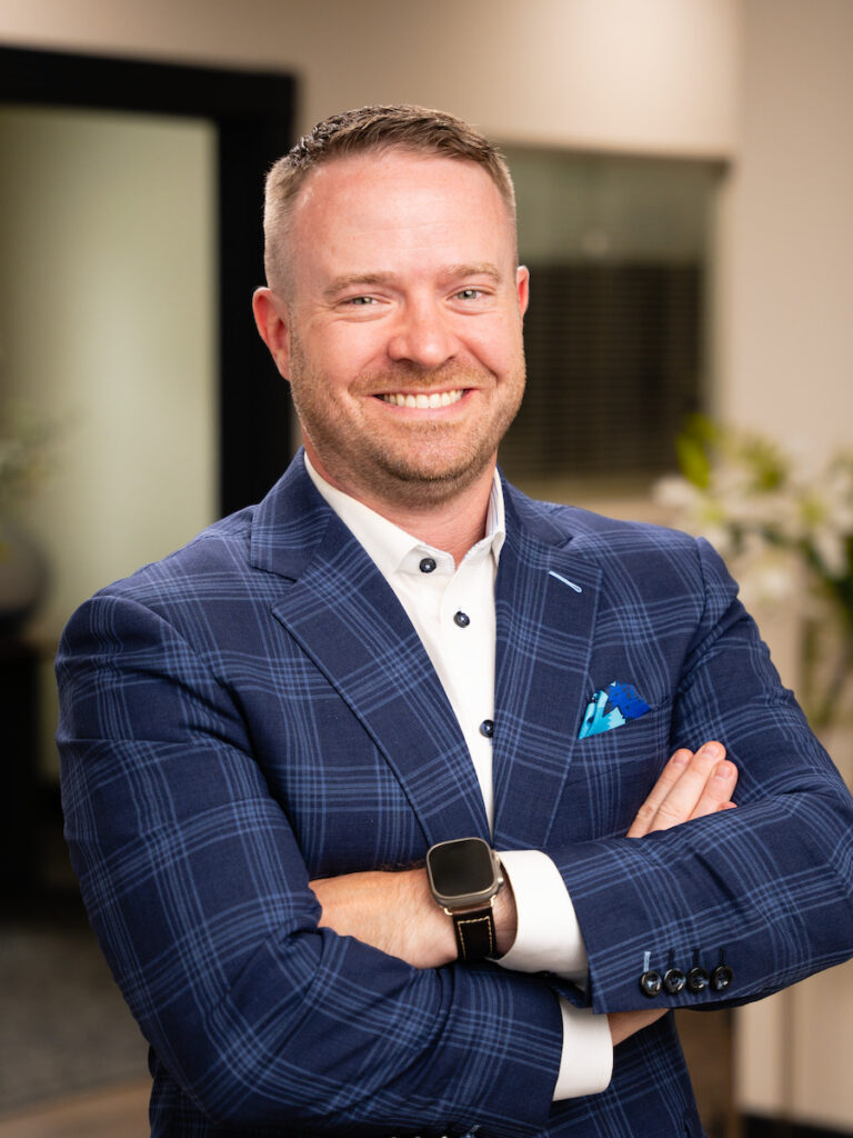 Net Revenue Employee, Tim, posing for headshot wearing white button up and blue blazer, smiling